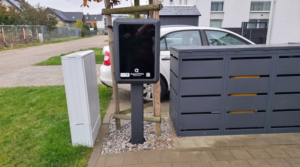 Closed AMP BOX wallbox cabinet on a pole installed on a residential driveway next to a utility box and bin shelter